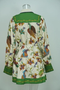 Detail of floral peacock print on long sleeve dress with green contrast pleated hem