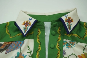 Detail of lapel collar with ethnic floral print and green fabric-covered buttons