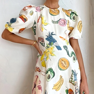 Détail des manches bouffantes et des imprimés de fruits et d'oiseaux sur la robe blanche