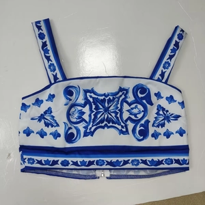 Detail of crop top featuring blue and white Majolica tile print and metal zipper closure