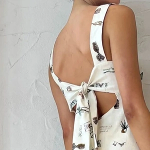 Détail d'une robe blanche sans manches avec un grand nœud au dos et un imprimé noir rétro