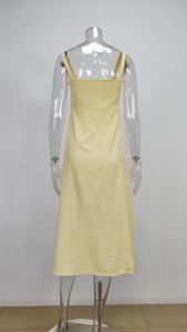 Back view of a light yellow floral slip dress with a high waist and elegant slit detail