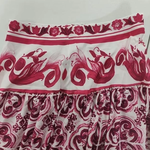 Close-up of white skirt with pink floral prints and fine pleated details on woven fabric