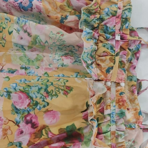 Detailed close-up of floral print dress featuring invisible zipper, white buttons and ruffles