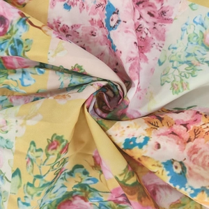 Detailed close-up of soft floral print fabric with pink flowers on yellow and white base