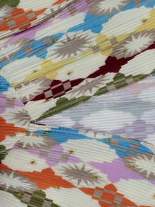 Detail of pleated dress fabric with vibrant geometric pop-art print and fine stitching