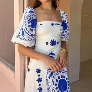 Detail of square neckline and puff sleeves on white floral dress with blue sun prints
