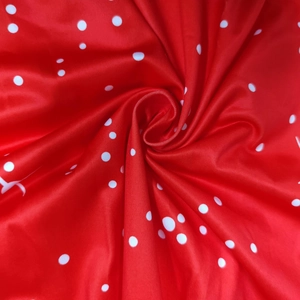 Détail macro du tissu rouge à pois blancs montrant texture lisse et drapé élégant
