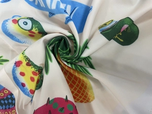 Close-up of vibrant summer holiday dress fabric with colorful cartoon fish and fruit prints