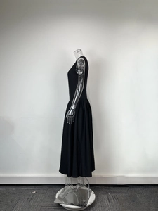 Vue latérale d'une élégante robe midi noire sans manches avec taille haute et jupe plissée sur mannequin
