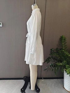 Detail view of white lantern sleeve dress with stand collar and tiered ruffle skirt hem