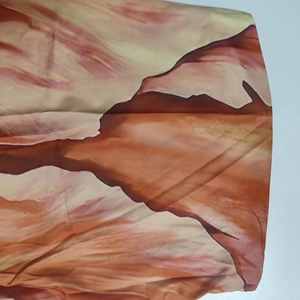 Close-up of vibrant orange and peach marble print fabric on a strapless maxi dress