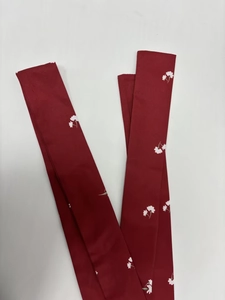 Détail d'une écharpe rouge à imprimé floral avec petites fleurs blanches sur tissu