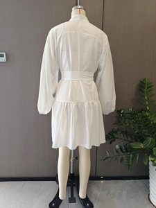 Detailed view of white puff sleeve dress with waist tie and tiered ruffle hemline
