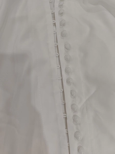 Macro shot of white spherical buttons and fabric loop closures on elegant dress placket