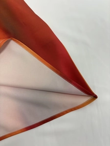 Détail de l'imprimé dégradé orange-rouge et de la couture fine sur l'ourlet de la robe