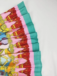 Detailed close-up of baroque print pleated skirt featuring gold chains and tassel motifs
