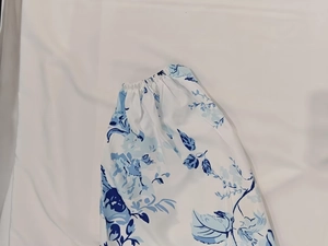 Detail of white dress with blue floral print featuring elastic waist and woven fabric texture