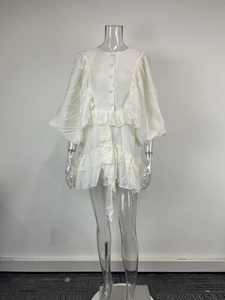 Detail view of the layered ruffles and textured fabric on a white waist-tie dress