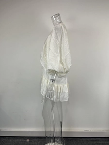 Detail of white puff sleeve dress featuring ruffled hem and textured fabric texture