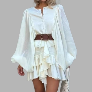 Detail of elegant cream ruffle dress featuring puff sleeves and brown leather belt