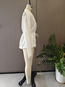 Side view of white long-sleeved blazer featuring a waist tie and notched lapel