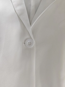 Close-up of white blazer notched lapel with high-quality matching resin button detail