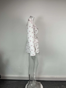 Détail d'un blazer blanc à fleurs avec col à revers et ceinture nouée à la taille
