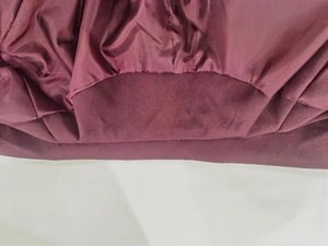 Detailed macro view of wine red jacket with ribbed knit cuff and smooth satin lining