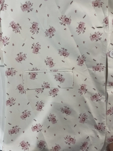 Détail d'un chemisier à imprimé floral avec une poche plaquée et un petit bouton blanc