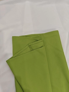 Détail du pantalon évasé vert herbe aux coutures soignées et texture de tissu plat premium