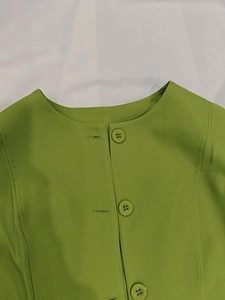 Détail du haut vert citron montrant le col rond élégant et les grands boutons assortis