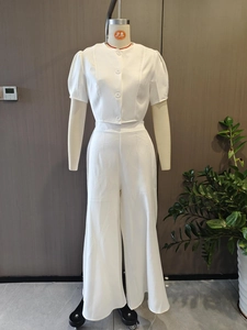 Détail d'un ensemble blanc deux pièces avec haut boutonné et pantalon large taille haute