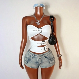 Détail d'un haut blanc ajouré avec boucles en métal et mini-short en jean délavé