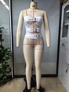 Détail d'un haut bandeau blanc ajouré avec trois boucles métalliques et tissu élastique