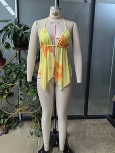 Detail of yellow halter neck top with orange floral patterns and irregular hem cut