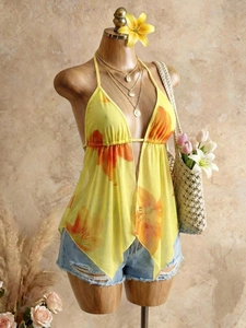 Floral halter top with deep V-neck and asymmetrical hem in orange and yellow print
