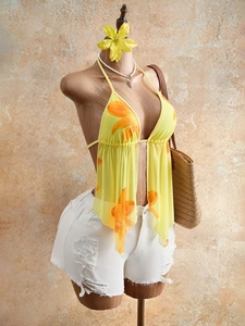 Floral mesh halter top with white distressed denim shorts for a stylish summer beach look