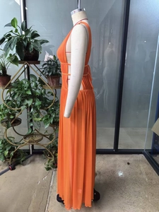 Detail of bright orange sleeveless maxi dress with cut-out waist and pleated fabric texture
