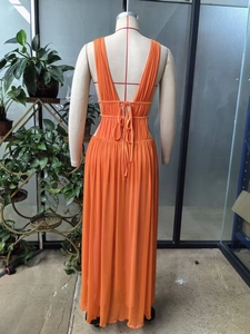 Detail of the backless orange maxi dress featuring thin crisscross lace-up straps