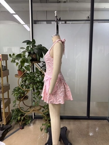 Detail eines rosa Jacquard-Blumenkleides mit großer Waisenschleife und Neckholder