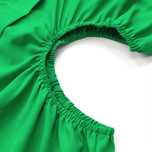 Vue macro des détails smockés élastiques d'une robe trapèze élégante de couleur vert Kelly
