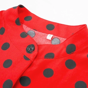 Détail de la combinaison rouge à pois noirs avec col montant et étiquette de taille S