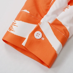 Detail of shirt cuff with orange and white artistic stripes and a single white button