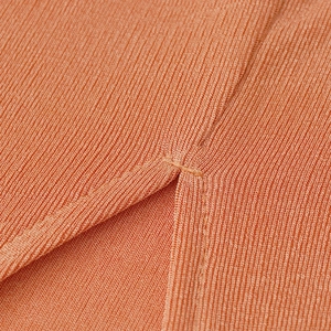 Gros plan détaillé sur la maille côtelée et la fente latérale de la robe orange
