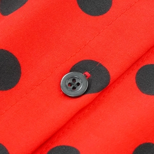 Vue détaillée du tissu rouge à pois avec bouton noir et texture textile fine