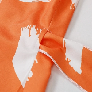 Detailed view of orange floral print fabric with cross tie waist and neat stitching