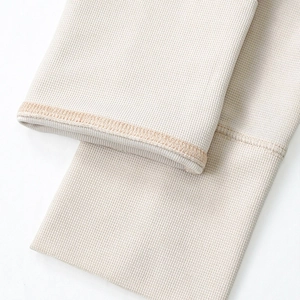 Close-up of beige waffle knit fabric texture and high-quality edge stitching detail