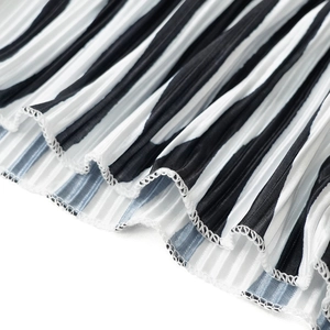 Macro detail of pleated zebra stripe fabric with fine white hem stitching on wide-leg pants