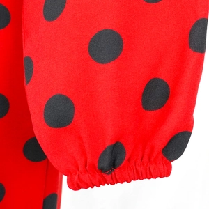Détail des poignets élastiques sur une combinaison rouge à pois à manches longues